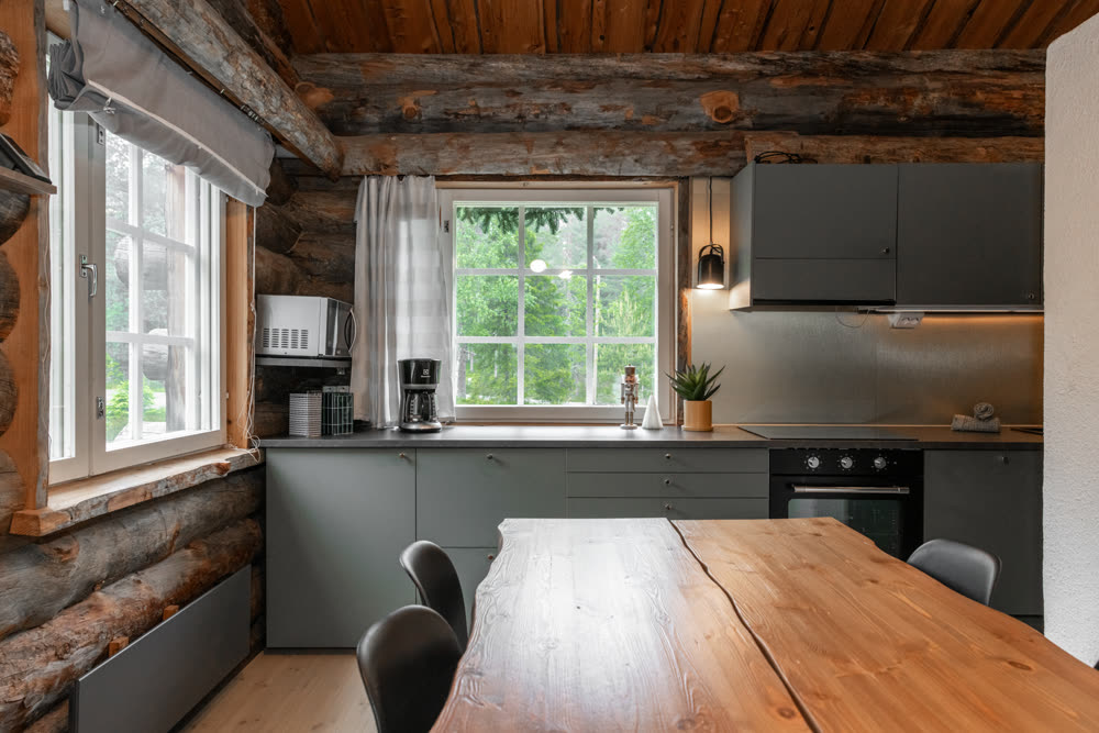 Dining table and kitchen with log walls and forest view